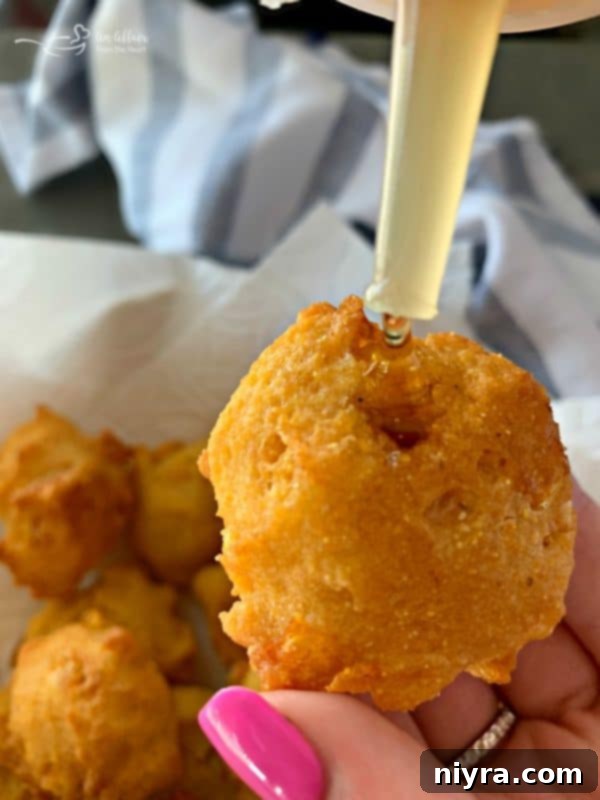 A child demonstrating how to fill a corn fritter with honey.