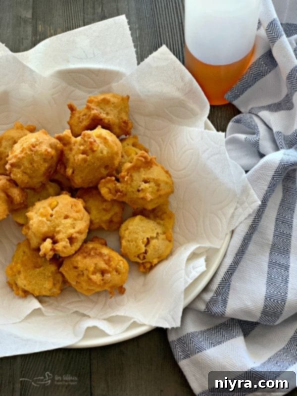 Freshly fried corn fritters draining on paper towels.