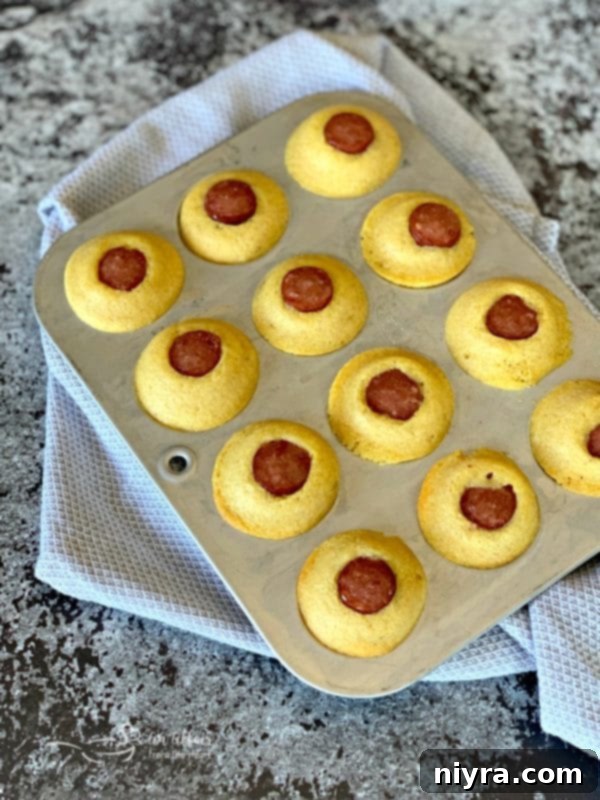 Freshly baked Corn Dog Mini Muffins in the muffin tin, ready to be removed