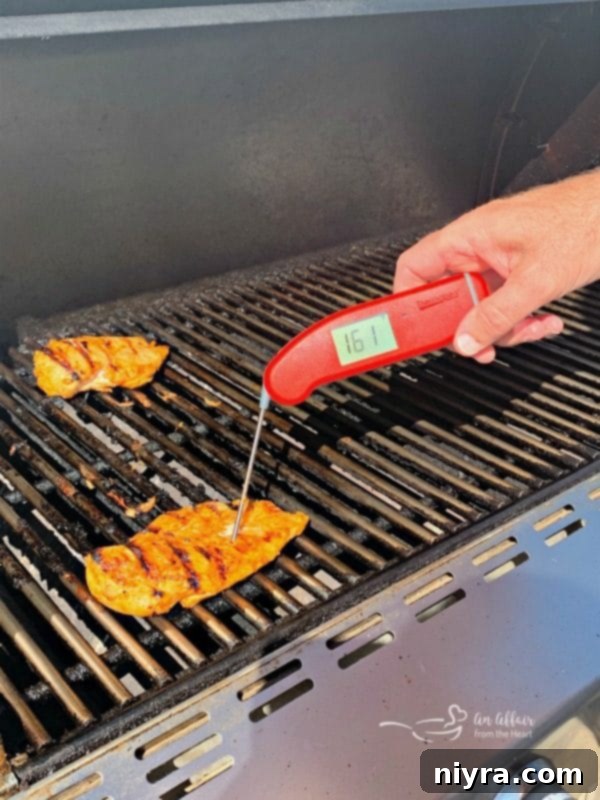 Chicken breasts grilling on a barbecue, developing a slight char and cooking to perfection for the tropical nachos.
