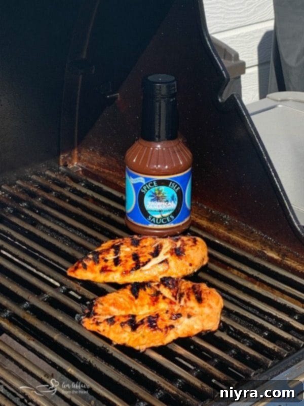 Grilling chicken breasts brushed with Spice Isle Tropical Tamarind Sauce, showing a delicious glaze and char.