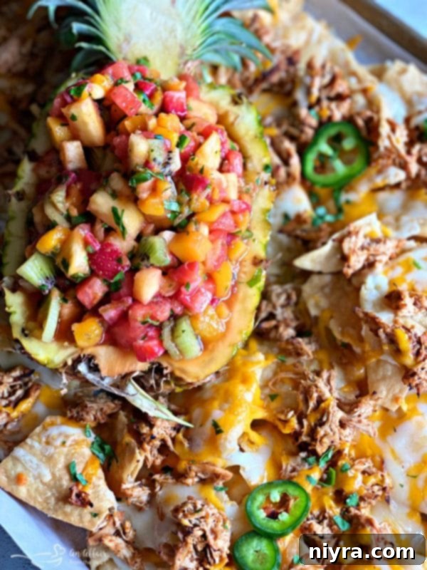 Close-up of Tropical Chicken Nachos with Tropical Salsa, showing melted cheese, shredded chicken, and fresh fruit salsa.