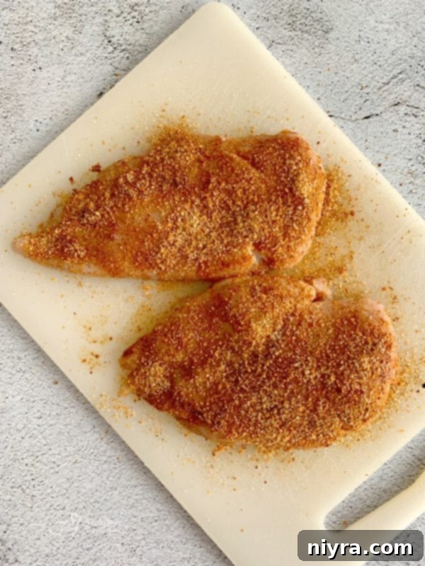 Chicken breasts seasoned with Spice Isle Tropical Seasoning Rub, ready for marination, highlighting the flavorful rub.