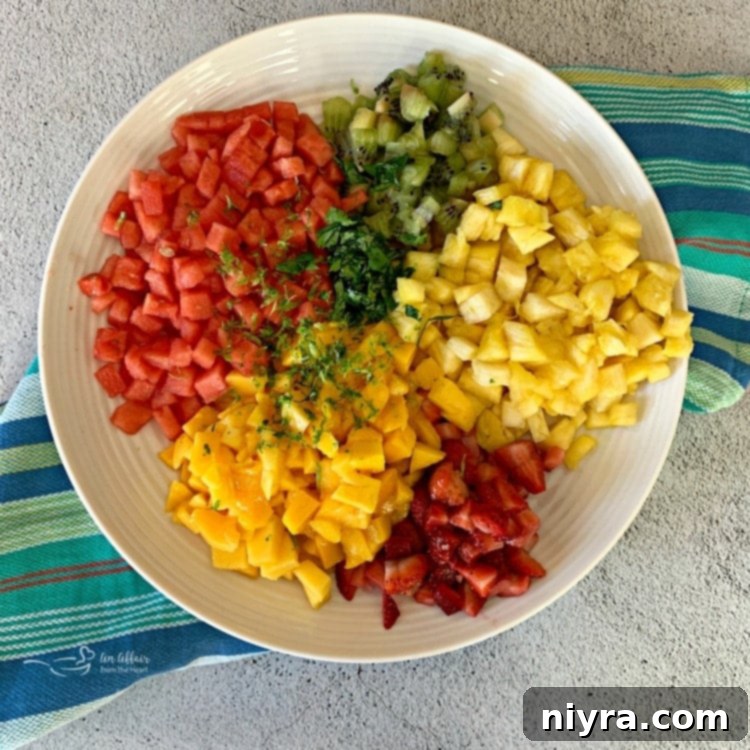 Ingredients for Tropical Salsa, including diced pineapple, kiwi, strawberries, mango, watermelon, and jalapeño, laid out for chopping.