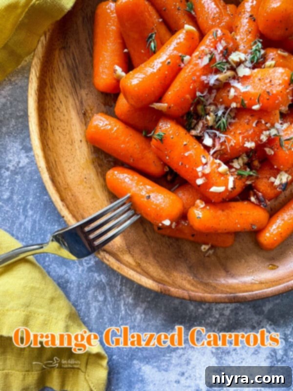A close-up of a serving of glistening orange glazed carrots with a fork, emphasizing their tender texture and the rich glaze.