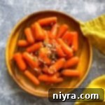 overhead of orange glazed baby carrots on a wooden plate.