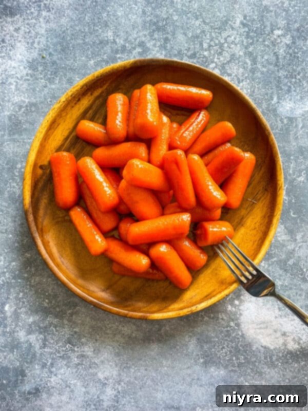 Close-up of freshly cooked orange glazed carrots in a bowl, showing their glossy coating and tender texture.