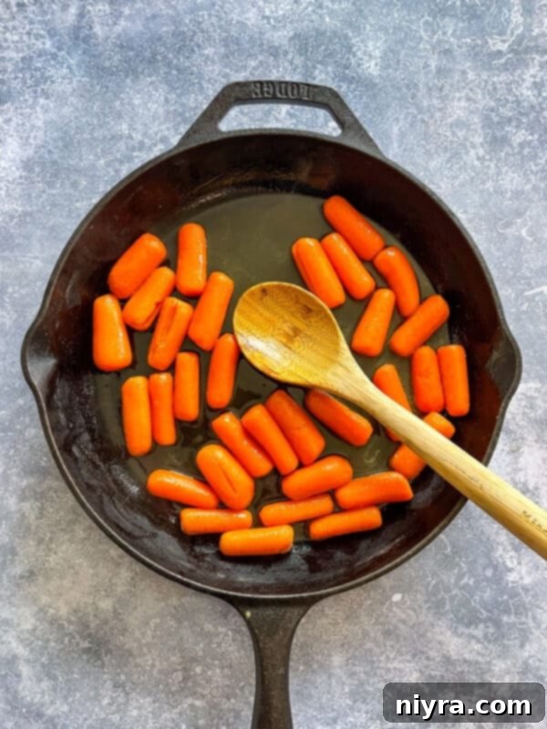 Step-by-step image showing orange juice, brown sugar, and butter added to drained carrots in a saucepan.