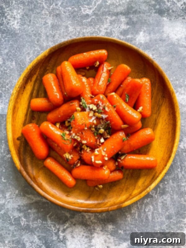 Perfectly cooked orange glazed carrots on a wooden serving board, ready to be enjoyed as a delicious side dish.