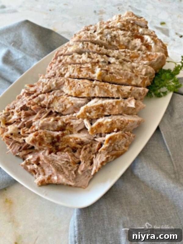 Moist and tender Fuggedaboutit Pork Roast served with creamy mashed potatoes and rich gravy on a plate, ready to enjoy for a comforting family meal.