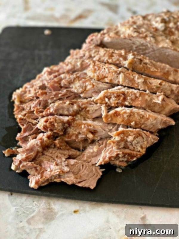 Tender Fuggedaboutit Pork Roast sliced on a cutting board, ready for serving.