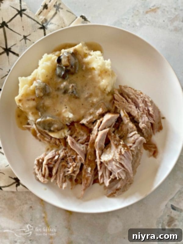 Delicious Fuggedaboutit Pork Roast served with mashed potatoes and gravy for a complete, comforting meal.