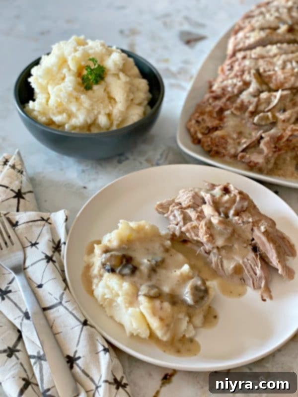 Fuggedaboutit Pork Roast plated with mashed potatoes and gravy, showcasing its tender texture and rich sauce.