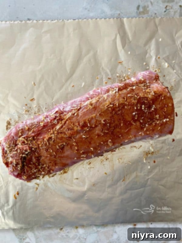 Pork loin roast being prepped on foil, rubbed with onion soup mix, ready for the next steps in making Fuggedaboutit Pork Roast.