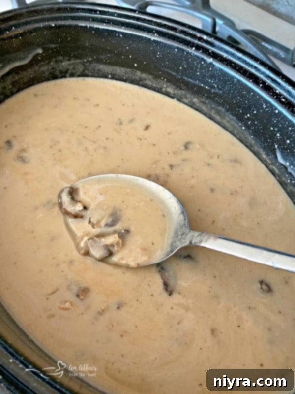 Homemade pork roast gravy, with or without mushrooms, in a serving bowl, made simply from the roast drippings.