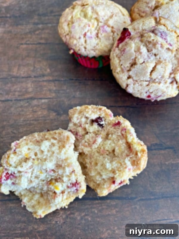 Delicious Cranberry Orange Muffins, one cut in half revealing its moist interior and fruit