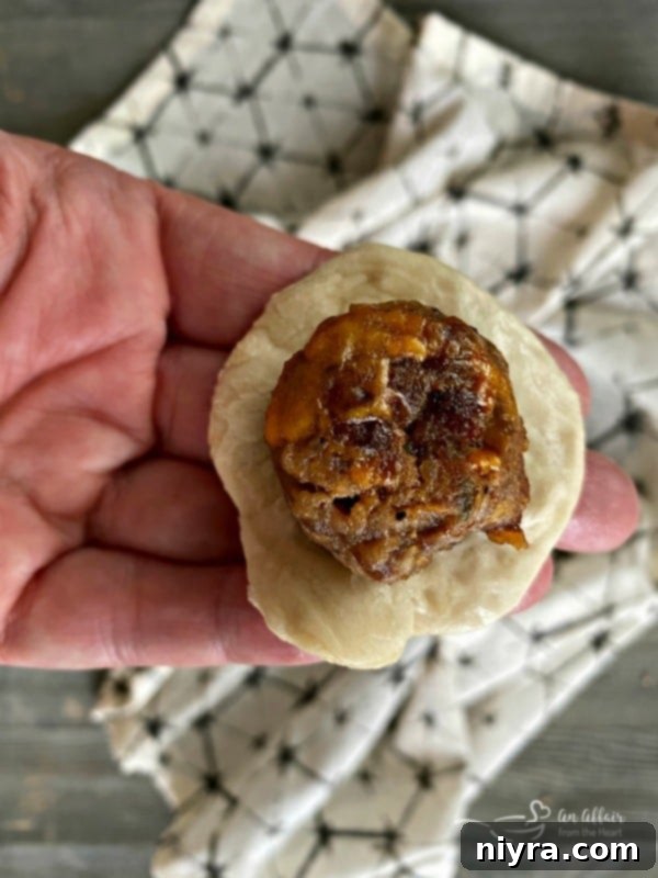 Sausage Pretzel Bombs with Tangy Cheese Dip 12 Sausage Pretzel Bombs prep: Meatball being wrapped in bread dough