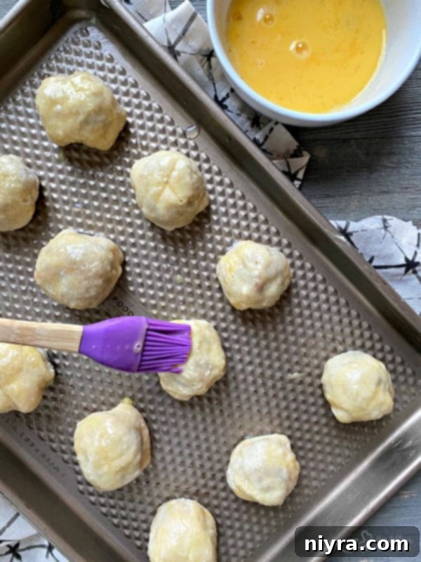 Sausage Pretzel Bombs with Tangy Cheese Dip 13 Sausage Pretzel Bombs prep: Applying egg wash before baking