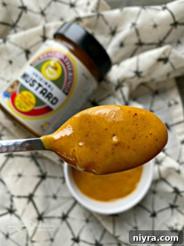 Sausage Pretzel Bombs with Tangy Cheese Dip 4 Herbal Gatherings Original Mustard on a wooden spoon