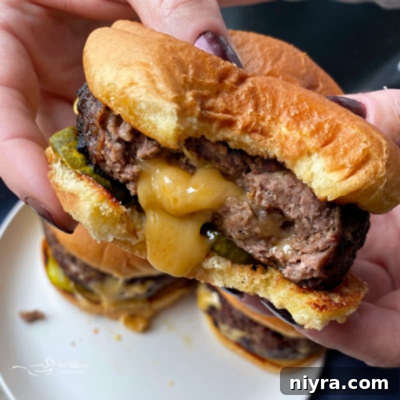 A close-up shot of a Juicy Lucy burger with a bite taken out, revealing the gooey, melted cheese inside.
