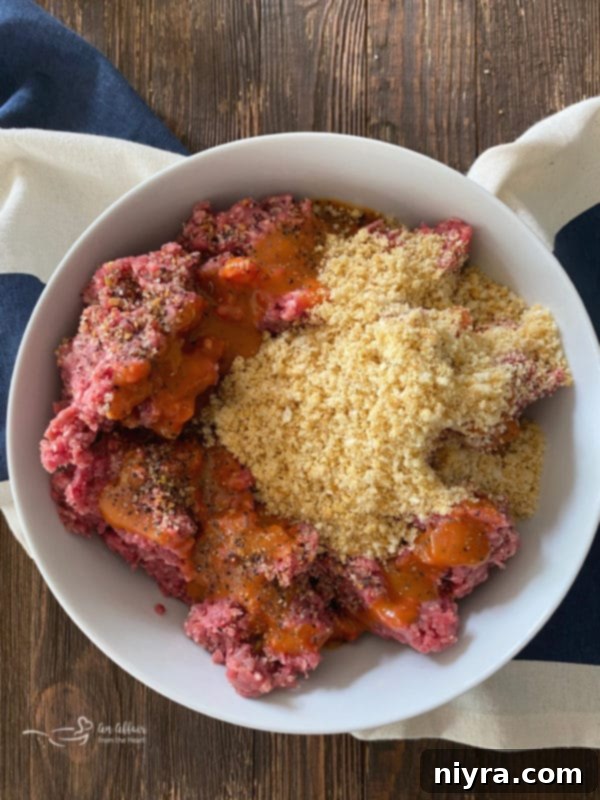 Close-up of mixing ground beef with Dorothy Lynch dressing, seasoning, and bread crumbs in a bowl.