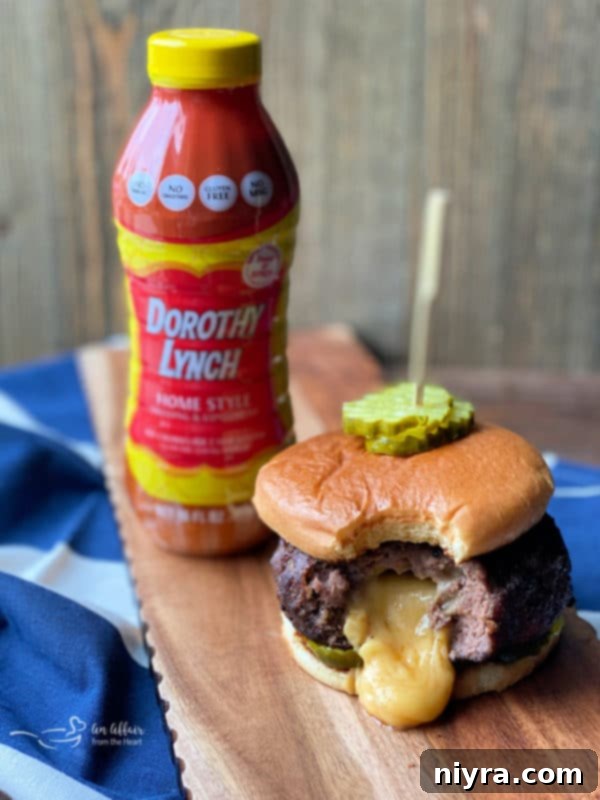 A close-up shot of a perfectly cooked Juicy Lucy burger on a toasted bun with dill pickles.