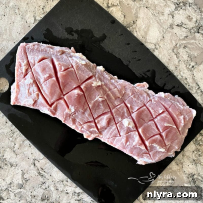 Succulent Smoked Pork Loin 5 Raw pork loin, expertly scored in a diamond pattern, resting on a cutting board, ready for marinating