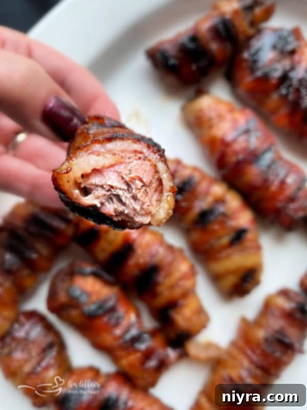 A close-up of a bite taken from a sweet and spicy bacon-wrapped pork rib, showcasing its tenderness.