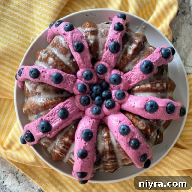Close-up of a slice of Blueberry Banana Bundt Cake with frosting and fresh blueberries