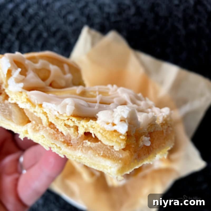 Close-up of a single Apple Bar, showing the flaky crust, cinnamon apple filling, and white glaze