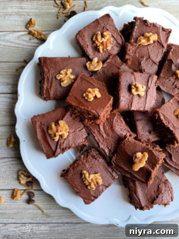 Decadent Chocolate Banana Bars 2 Delicious Chocolate Banana Bars on a white plate, garnished with walnuts and a rich chocolate frosting.