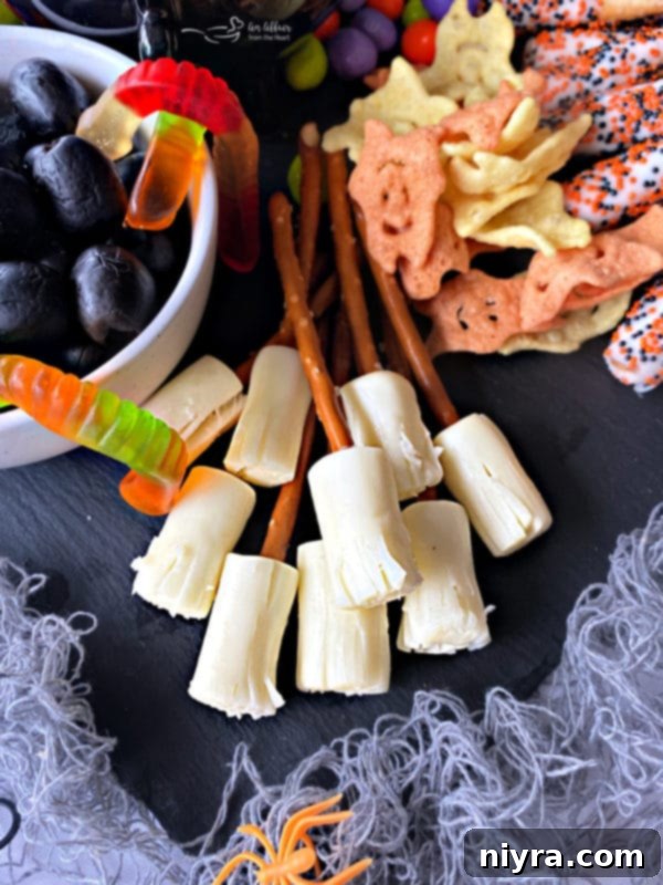 Spooky Sweet and Savory Halloween Snack Board with Peanut Butter Dip 5 Close-up of the edible witch brooms made from pretzel sticks and string cheese on the Halloween snack board.