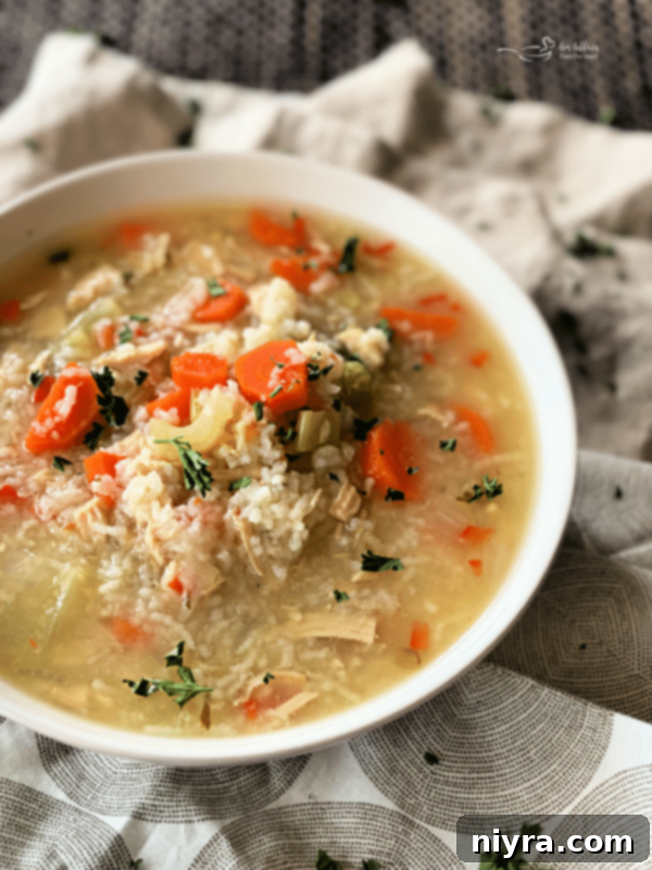 Hearty Instant Pot Chicken and Rice Soup 4 A bowl of creamy Instant Pot Chicken and Rice Soup with a spoon