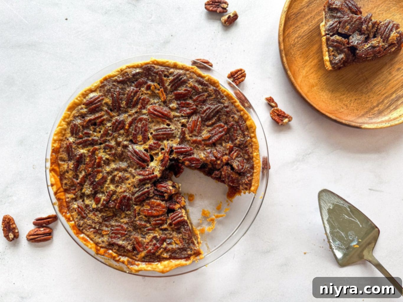 Pecan pie with one slice missing on a white plate