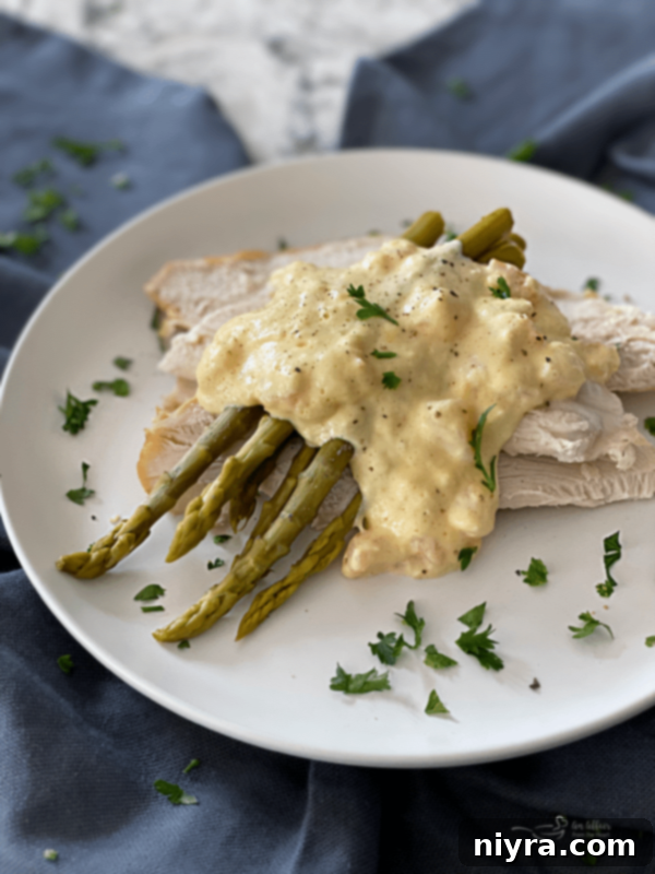 A stunning plate of Turkey Oscar featuring sliced turkey breast, green asparagus spears, a generous topping of shrimp and crabmeat, all draped in a golden Hollandaise sauce, ready to be enjoyed.