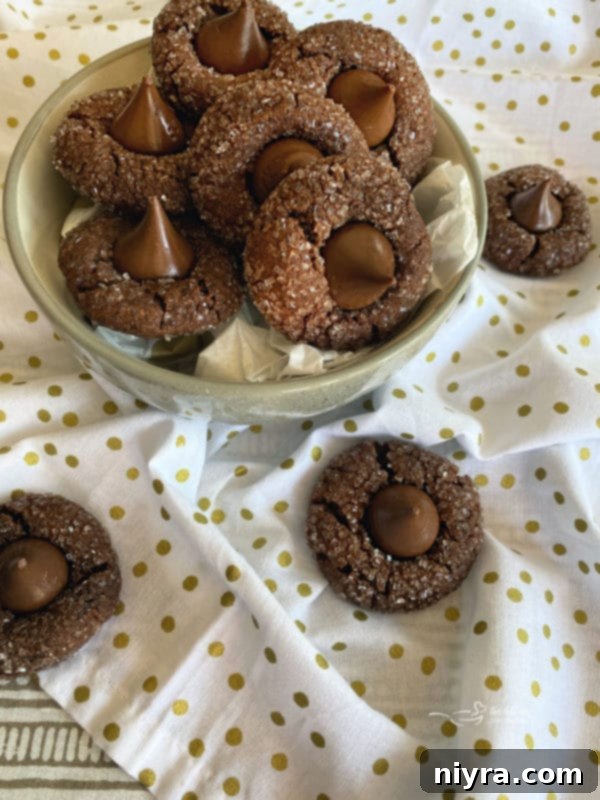 Three Chocolate Sugar Kiss Cookies arranged on a white plate, showing their rich chocolate color and sparkly coating, ready to be enjoyed.