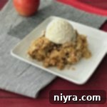 The Very BEST Apple Crisp topped with ice cream on a white plate