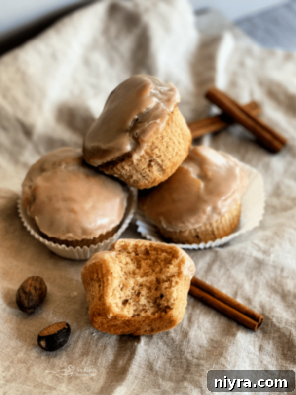 Glistening Spice Muffins 2 Delicious Spiced Glazed Muffins on a khaki background, showcasing their perfect golden-brown tops and glistening glaze