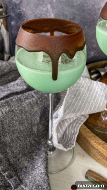 Emerald Dream 3 Close-up of a Grasshopper Cocktail with a chocolate-rimmed glass, topped with whipped cream and mint sprig.