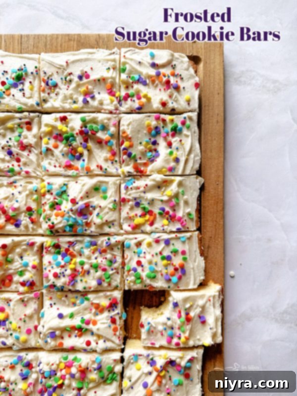 A large pan of freshly baked Frosted Sugar Cookie Bars, decorated with colorful sprinkles.