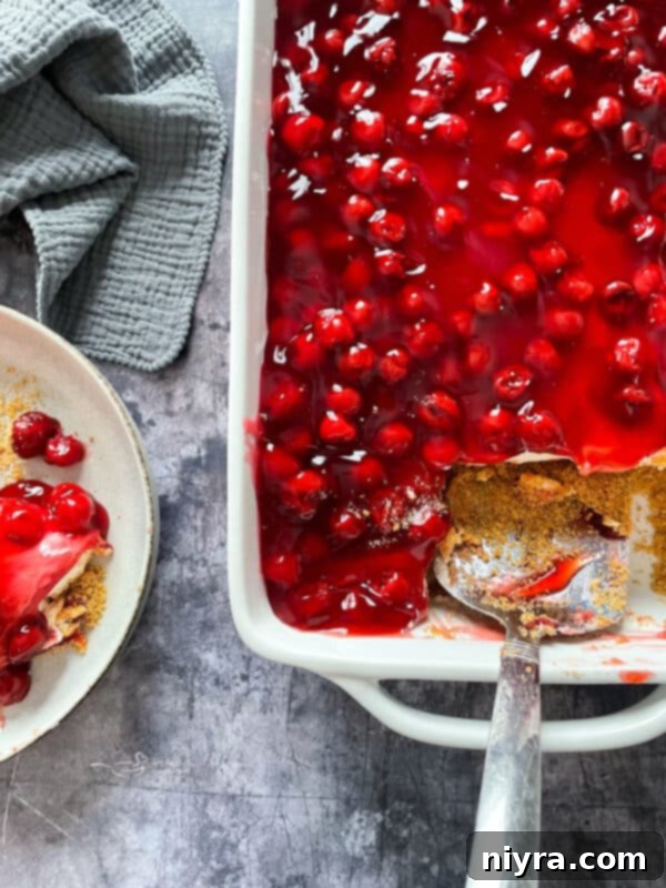 Crimson Cherry Indulgence 3 Overhead view of a No-Bake Cherry Dessert in a rectangular baking dish, topped with red cherries.
