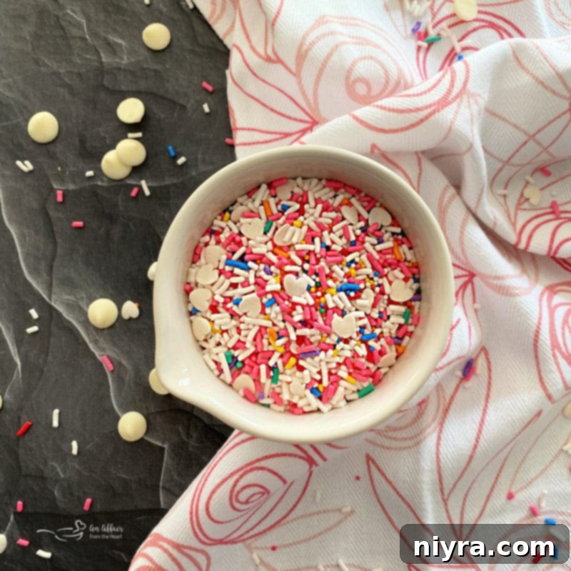 Overhead shot of pink fudge in a square pan with colorful sprinkles