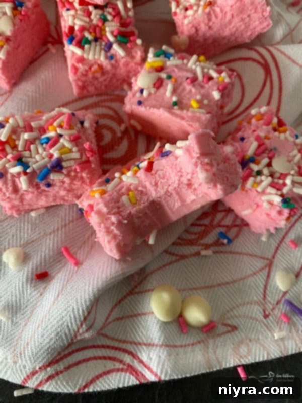 More pink fudge with heart sprinkles on a wooden surface