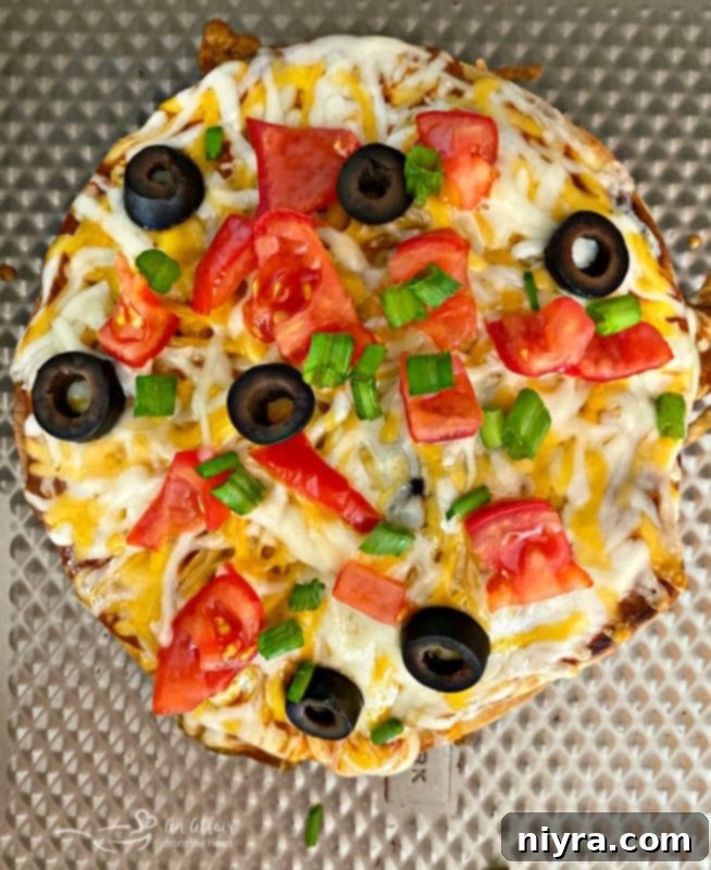 An overhead shot of a delicious copycat Taco Bell Mexican Pizza served on a metal baking surface, showcasing its crispy tortillas and savory toppings.