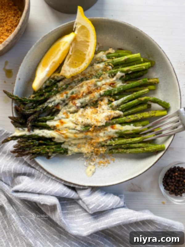 Garlic cheese asparagus in plate with lemon wedges and cheese