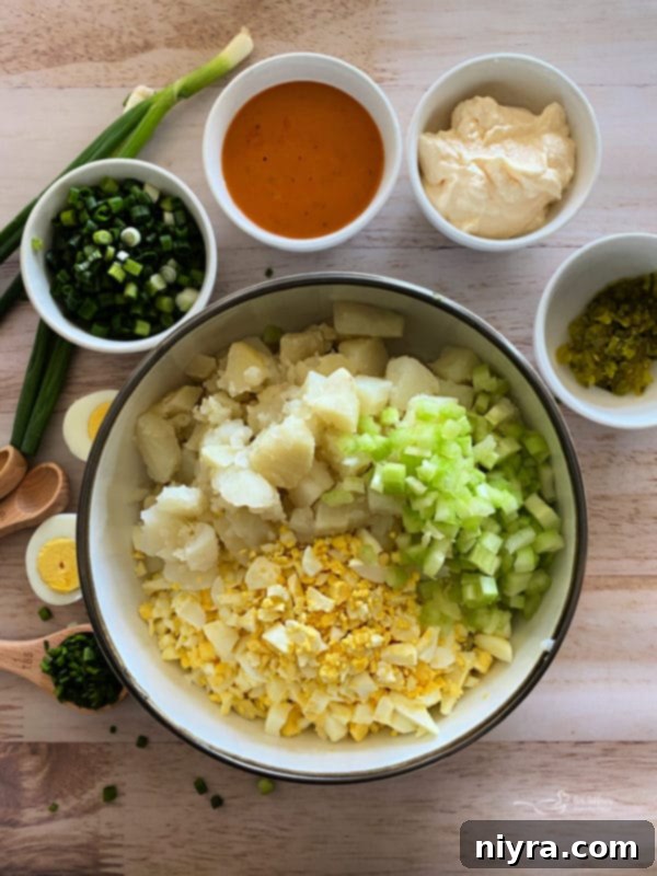 A large bowl filled with various chopped ingredients for potato salad: cooked potatoes, celery, green onions, and hard-boiled eggs.