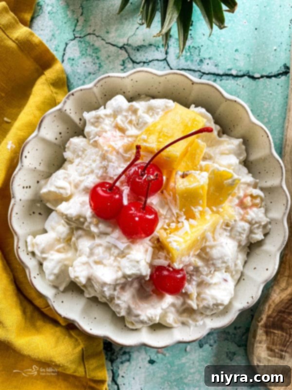 Top view of piña colada fluff salad with cherries, garnished with fresh mint.