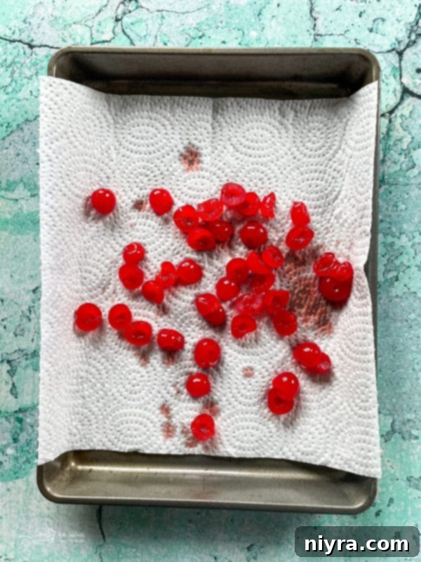 Bright red maraschino cherries neatly arranged on a baking sheet, ready for preparation.