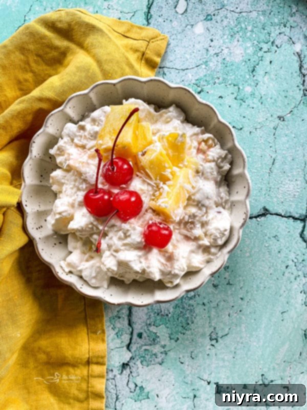 A large bowl of pineapple fluff with cherries and diced pineapples, garnished and ready to serve.
