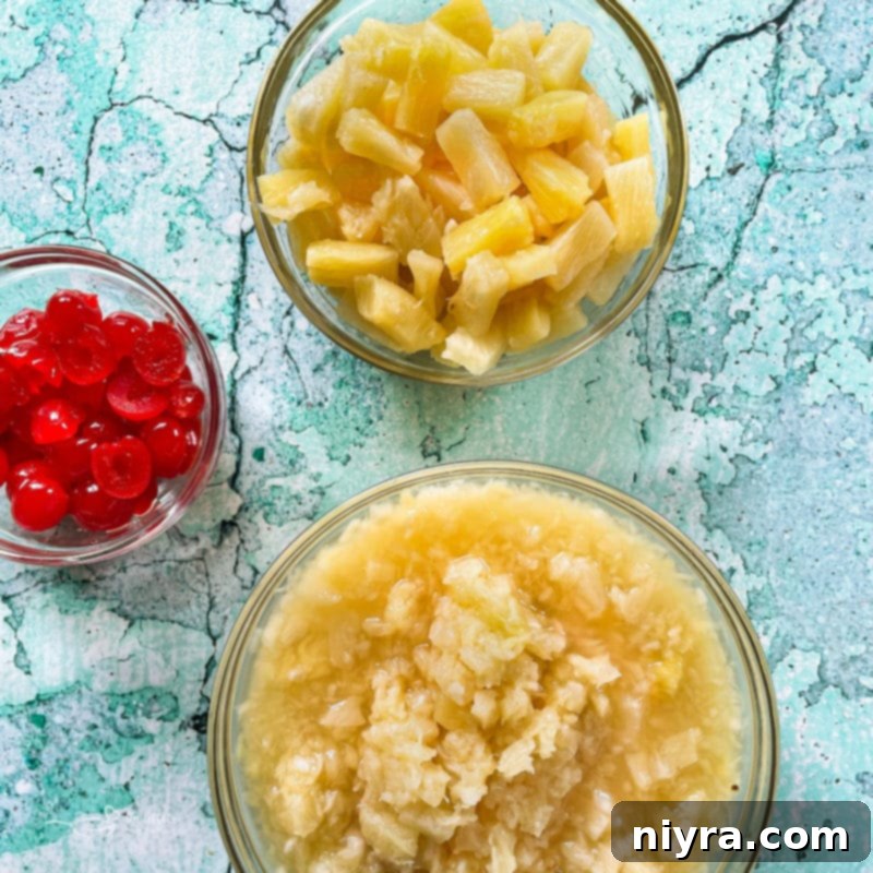 Arrangement of fresh pineapple slices, diced pineapple, and a bowl of bright red maraschino cherries.